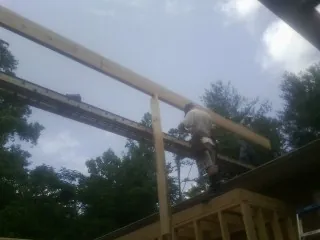 Carpenter setting a ridge beam over a new addition frame — Ice Dam Removal by Roofing Brothers in Barclay