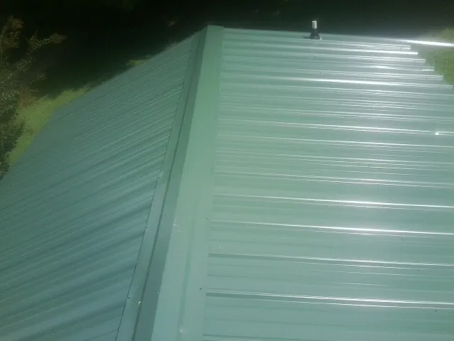 New green metal panels meeting at the ridge of a roof — Flat Roof Repair work by our crew in Barclay