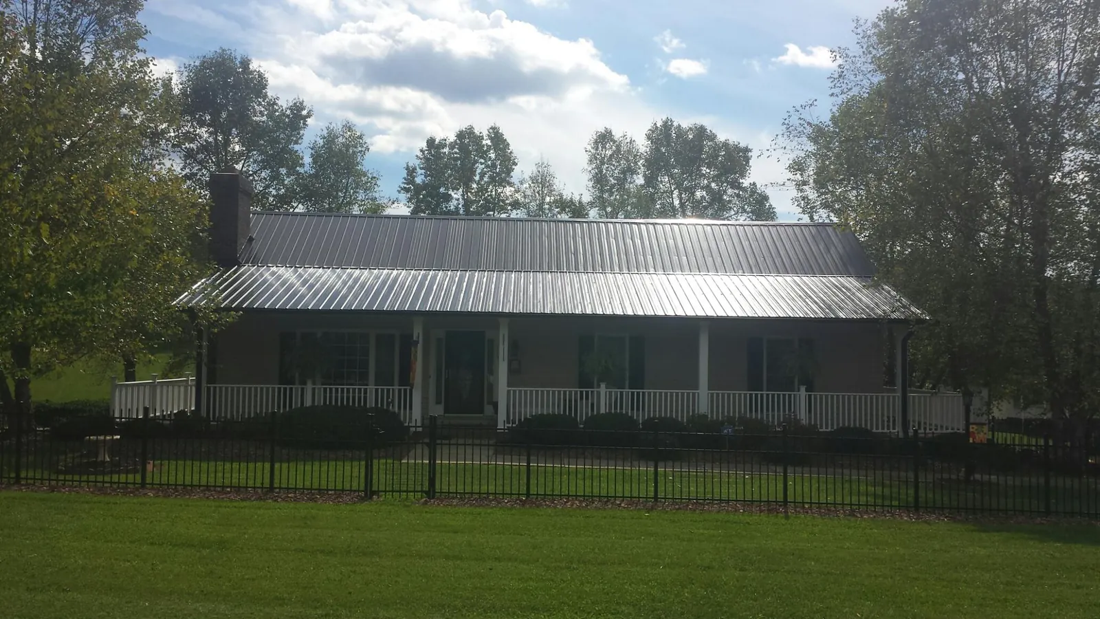 Gray metal roof on a brick ranch with a full width front porch — Gutter Guard Installation work by our crew in Barclay